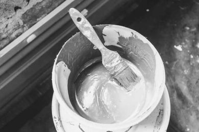 paintbrush inside a bucket of paint